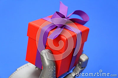 Robot hand holds a gift. Concept - robot congratulates Stock Photo