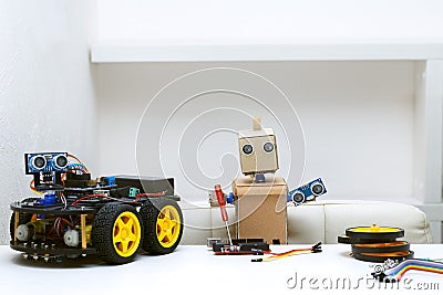 The robot holds in its hands the parts for assembling the robot, and next to it is a robot with wheels Stock Photo