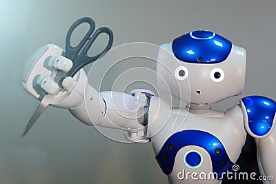 Robot holds scissors in his hand. Hairdresser. A small robot with a human face and a humanoid body. Artificial intelligence-AI. Editorial Stock Photo