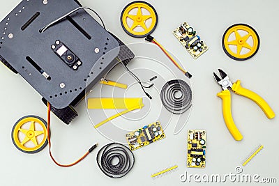 Robot on wheels and yellow tools. Flat lay Stock Photo