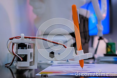 Robotic arm with orange pen drawing portrait at robot futuristic exhibition Stock Photo
