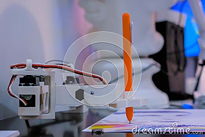 Robotic arm with orange pen drawing portrait at robot futuristic exhibition Stock Photo