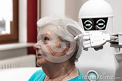 A robotic caregiver is combing the hair of a female senior adult Stock Photo