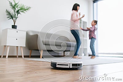 Robotic device collecting dust while mom and child dancing Stock Photo