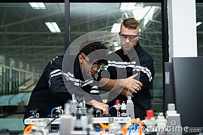 The robotic hand technology teacher is instructing new students on how to use electronic circuit boards and robotic hand commands Stock Photo