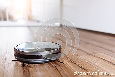 Robotic vacuum cleaner on laminate wood floor smart cleaning technology. Selective focus. Stock Photo