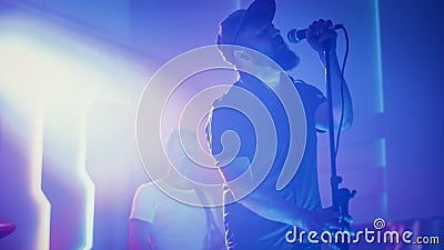 Rock Band Performing at a Concert in a Night Club. Portrait of a Lead Singer Singing into Micropho Stock Photo