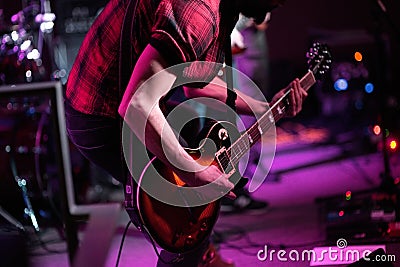 Rock band performs on stage. Guitarist, bass guitar and drums. The guitarist plays Stock Photo