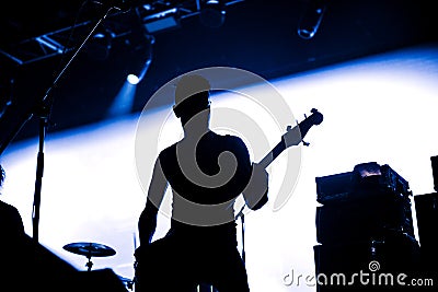 Rock band performs on stage. Guitarist plays solo. silhouette of guitar player in action on stage in front of concert crowd. Close Editorial Stock Photo