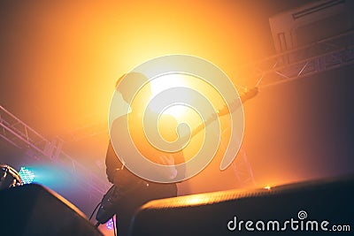 Rock band performs on stage. Guitarist plays solo. silhouette of guitar player in action on stage in front of concert crowd. Stock Photo