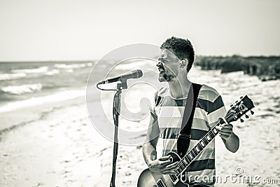 Rock on the beach, the musician plays the guitar and sings into the microphone, the concept of leisure and creativity Stock Photo