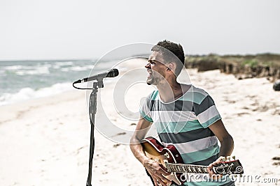 Rock on the beach, the musician plays the guitar and sings into the microphone, the concept of leisure and creativity Stock Photo