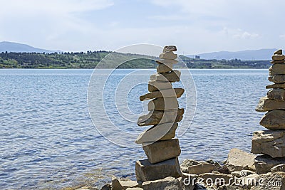 Rock cairn the art of stone balancing on a stone near a blue water flowing lake. Stock Photo