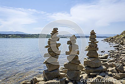 Rock cairn the art of stone balancing on a stone near a blue water flowing lake. Stock Photo