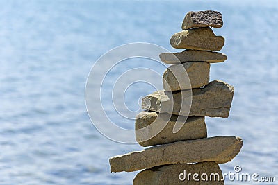 Rock cairn the art of stone balancing on a stone near a blue water flowing lake. Stock Photo