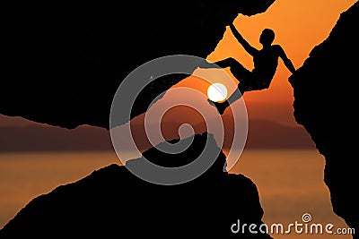 Silhouette man Climbing between rocks with red sky sunset background Stock Photo