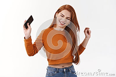 Rock-on. Excited and carefree attractive modern redhead woman having fun, enjoying awesome music favorite artist, made Stock Photo