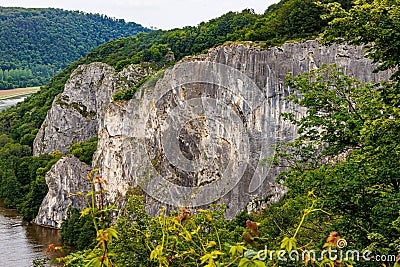 Rock formation known as Freyr Rocks, among hills with green leafed trees Stock Photo