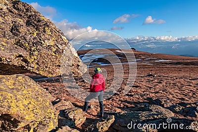 Rock formation and woman with ear flap hat standing on alpine meadow with scenic view on Grosser Sauofen (Ebersteiner Sau) Stock Photo