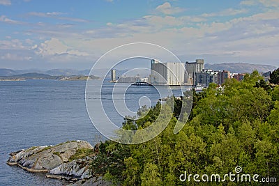 Rock island with trees with the silo`s and apartment buildings of Stavanger harbor beyond Editorial Stock Photo