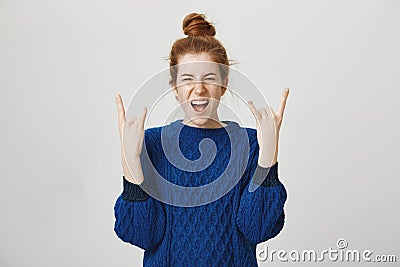 Rock n roll lives in us. Portrait of excited and thrilled young european redhead girl screaming from positive emotions Stock Photo