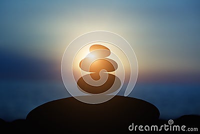 Rock pebble pyramid silhouette at sunset light, zen stones on sea beach, meditation, spa, harmony, calm background, balance concep Stock Photo