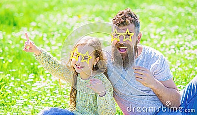 Rock star concept. Dad and daughter sits on grass at grassplot, green background. Family spend leisure outdoors. Child Stock Photo