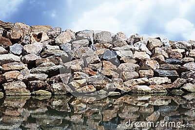 Rock wall protection from the waves agaist a a blue sky Stock Photo