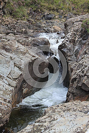 Rock wedged between two rock faces with water rushing around it Stock Photo