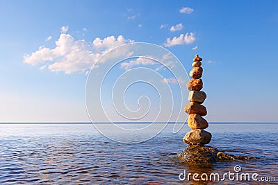 Rock zen pyramid of colorful pebbles standing in the water on the background of the sea Stock Photo