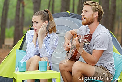 Rockman playing guitar and bored woman Stock Photo