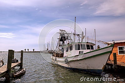 ROCKPORT, TX - 3 FEB 2020: White and green shrimp boat tied by rope to the wooden dock in a marina Editorial Stock Photo
