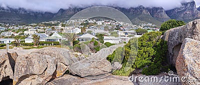 Rocks and boulders against a majestic mountain and cityscape background with lush green plants and coulds. Remote and Stock Photo