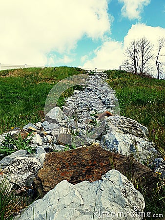 Rocks climbing a hill jagged and sticking out all different colors brown gray green blue Stock Photo