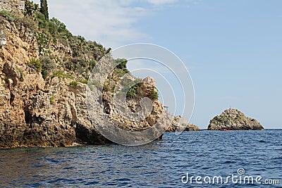 Rocks falling into the sea, covered with cacti and plants, rocks and the coast of the Ionian Sea, Sicily Stock Photo