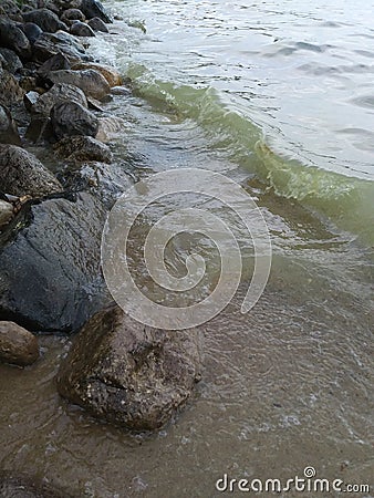 Rocks Lake trees pebbles waves water sky clouds vegetation beach evening view scenic Stock Photo