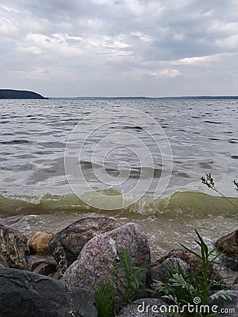 Rocks Lake trees pebbles waves water sky clouds vegetation beach evening view scenic Stock Photo