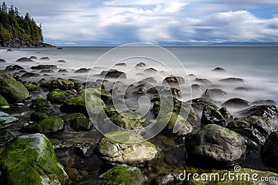 Rocks in the Mystic beach surrounded by the sea with long exposure in Canada Stock Photo