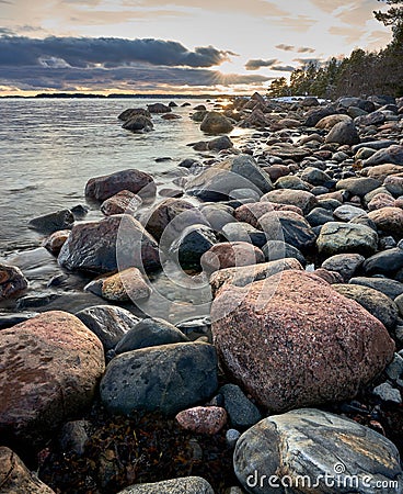 Rocky beach with an abundance of stones and the glistening waters in the backdrop Stock Photo