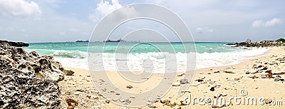 Rocky beach view at Caribbean sea coast, with light blue sky and white clouds. Sunny beach landscape with rocks and huge foamy Stock Photo