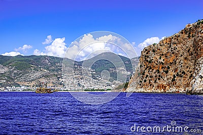 Rocky coast of Alanya Turkey and a ship in the blue water of the Mediterranean Sea. Beautiful panorama of the Turkish Riviera Stock Photo