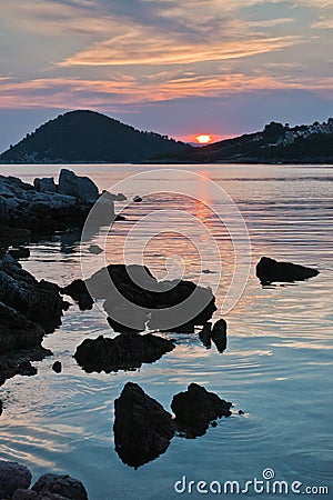 Rocky coast and calm water of Panormos bay at sunset, Skopelos island Stock Photo