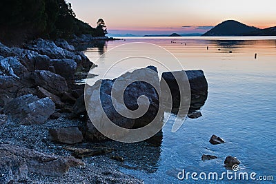 Rocky coast and calm water of Panormos bay after sunset, Skopelos island Stock Photo
