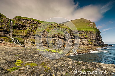 Rocky coastline with cliffs and waterfalls at village Mikladalur, Kalsoy island, Faroe Islands Stock Photo