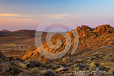 Rocky desert at dusk, colorful sunset over the Namib desert, Namibia, Africa, glowing rocks and canyon. Stock Photo