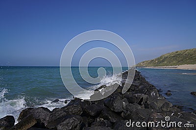 Rocky stone line in the sea with the wave foam touching the stones Stock Photo