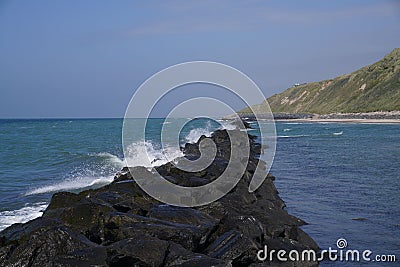 Rocky stone line in the sea with the wave foam touching the stones Stock Photo