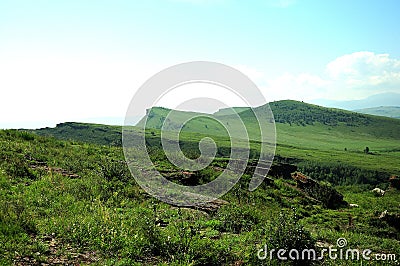 A rocky top of a high hill overlooking a fertile valley on a sunny summer day Stock Photo