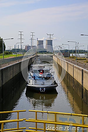 View on lock sluice at river Maas with cargo ship, blurred towers of RWE power station background Editorial Stock Photo