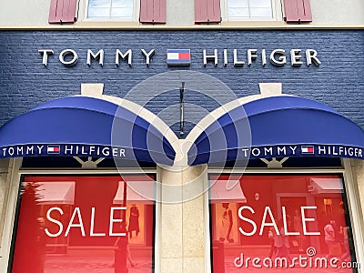 View on store facade with logo lettering of tommy hilfiger and red sale signs in window Editorial Stock Photo